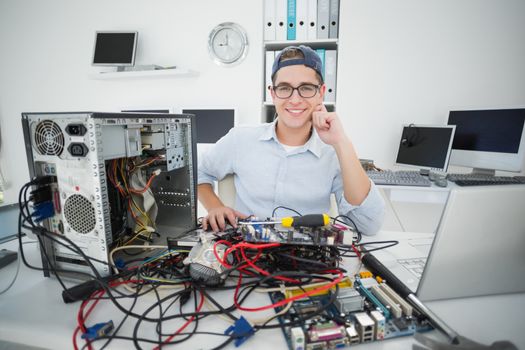Smiling technician working on broken computer in his office