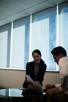 Business people discussing over document while sitting at office