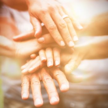 Happy volunteer family putting their hands together on a sunny day