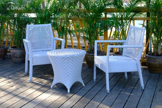 CloseUp of plastic weave chairs and table in outdoor terrace. Wicker weave outdoor Plastic furniture white color. 