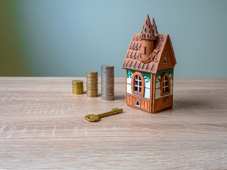 Model of a house, Stack of European Euro coins and golden key On Wooden Table. Real estate agency, mortgage loan, lottery, buying property.Home loan and investment concept. Copy space