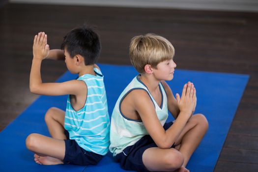 Side view of siblings performing yoga at home
