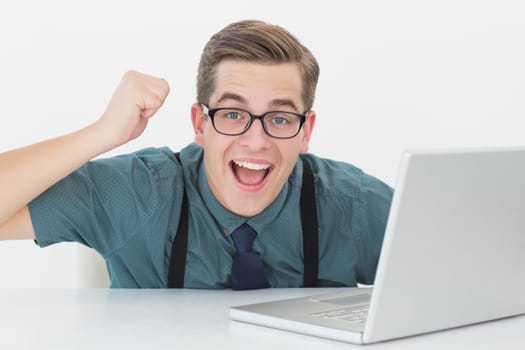 Nerdy businessman at his desk looking at laptop in his office