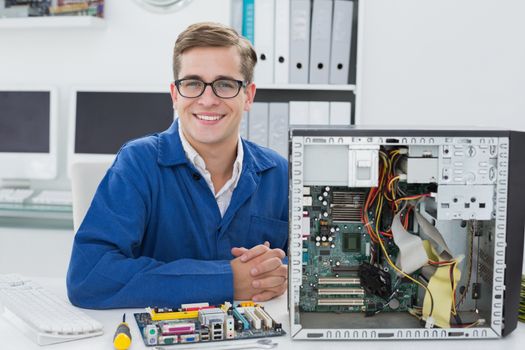 Smiling technician working on broken computer in his office