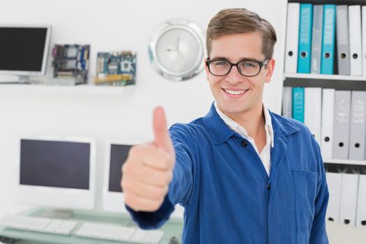 Smiling technician looking at camera showing thumbs up in his office