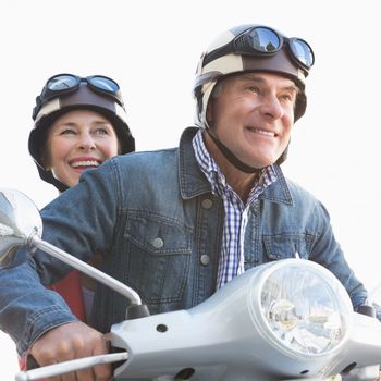 Happy senior couple riding a moped on a sunny day