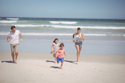 Happy family running at beach during sunny day