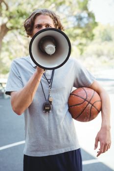 Male basketball coach using megaphone outdoors