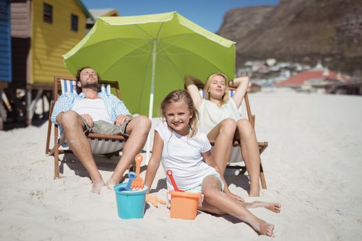 Family relaxaing at beach during sunny day