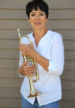 Mature female trumpet player expressions with her horn outside.