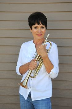 Mature female trumpet player expressions with her horn outside.