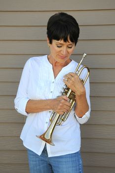 Mature female trumpet player expressions with her horn outside.