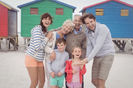 Portrait of happy multi-generation family standing against beach huts