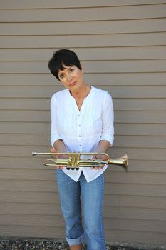 Mature female trumpet player expressions with her horn outside.
