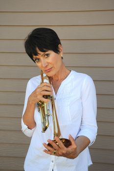 Mature female trumpet player expressions with her horn outside.