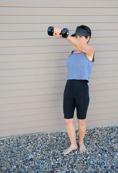 Mature female beauty working out with hand weights outside.