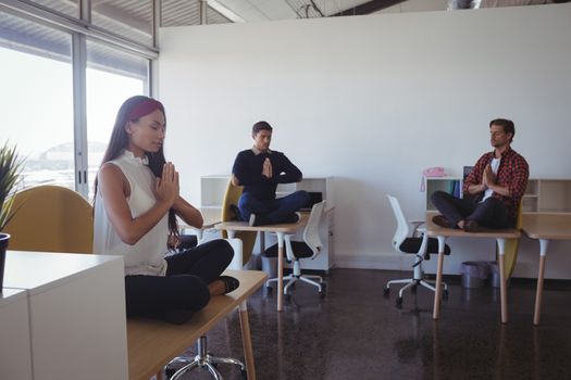 Business people doing yoga while sitting on desk at office