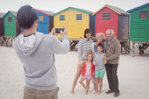 Man photographing family standing at beach