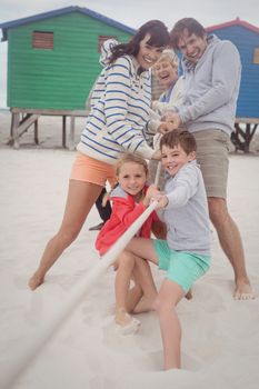 Happy multi-generation family playing tug of war at beach