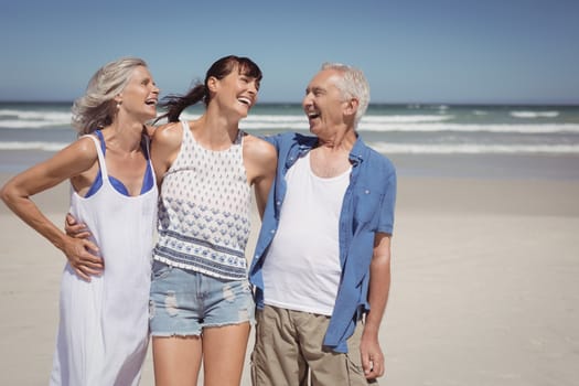 Cheerful family standing at beach during sunny day