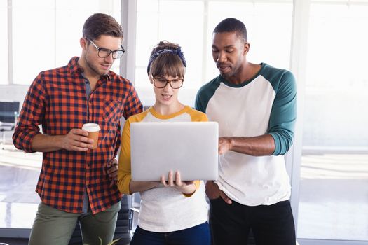 Business people using laptop while standing by desk in office