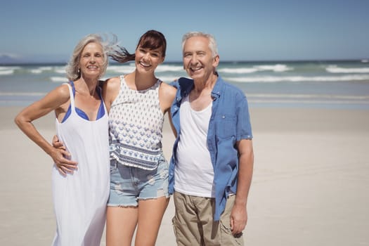 Portrait of family standing at beach during sunny day
