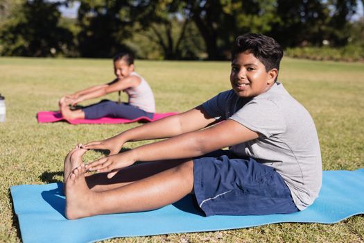 Portrait of boy touching toes during yoga glass on exercise mat at park