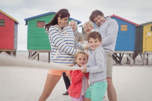 Multi-generation family playing tug-of-war at beach