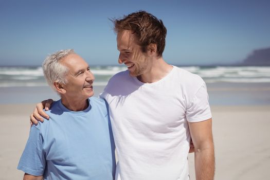 Happy family standing at beach during sunny day