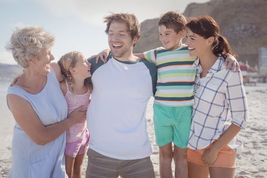 Happy multi-generated family at beach during sunny day