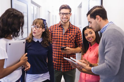 Business people using technologies while standing n=in corridor