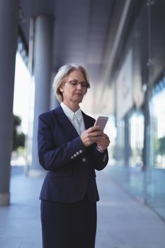 Businesswoman using smart phone while standing on sidewalk