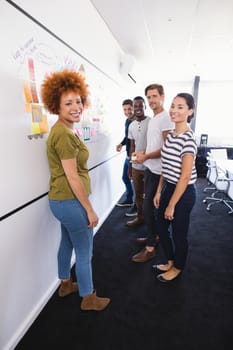 Portrait of business people standing by whiteboard in office