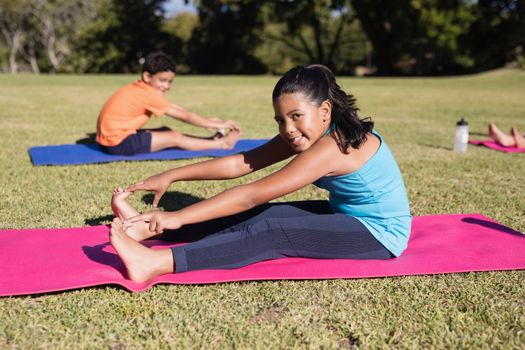 Portrait of girl touching toes during yoga glass on exercise mat at park