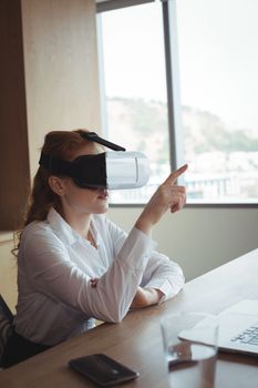 Businesswoman anticipating while using virtual reality technology at desk in office