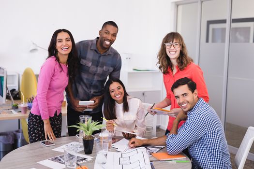 Smiling business people at desk against wall in office