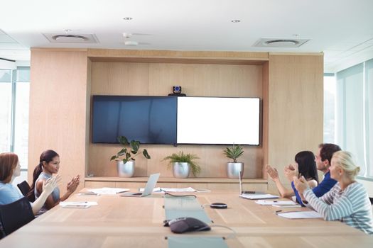 Business people clapping during meeting in board room