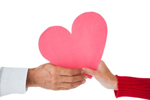 Couple passing a paper heart on white background