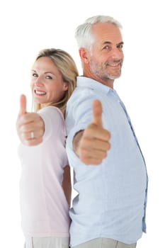 Smiling couple showing thumbs up together on white background