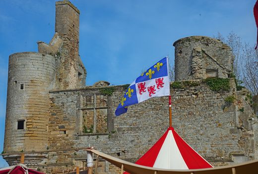 Top of medieval red and white tent with normandy flag at top and castle in background