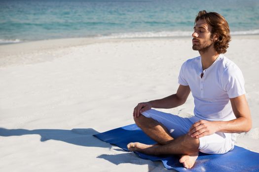 Man performing yoga at beach on a sunny day