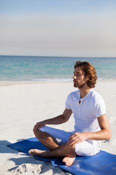 Man performing yoga at beach on a sunny day