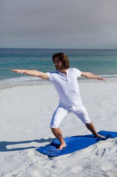 Man performing yoga at beach on a sunny day