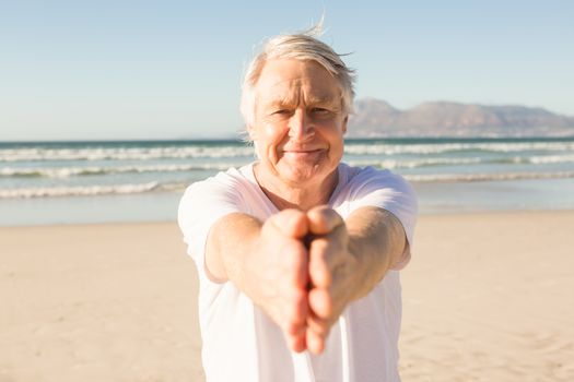 Portrait of senior man practicing yoga at beach on sunny day
