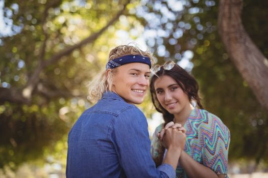 Portrait of romantic couple holding hands against trees