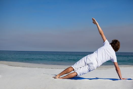 Man performing yoga at beach on a sunny day