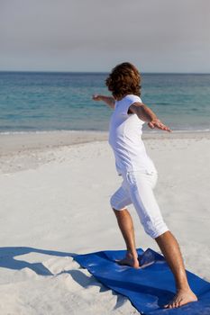 Man performing yoga at beach on a sunny day