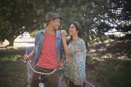 Romantic couple standing with bicycle on footpath