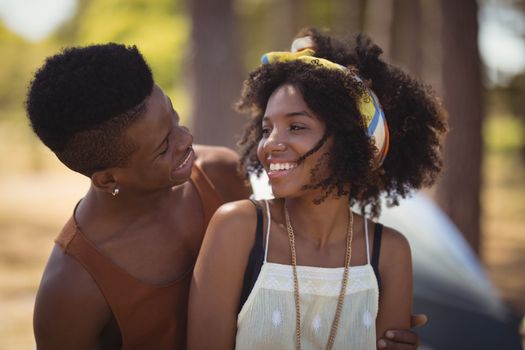 Close up of smiling romantic couple sitting against tent on field