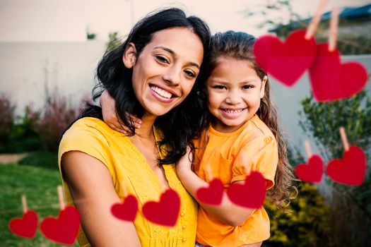 Hearts on line against portrait of mother holding her daughter outdoors